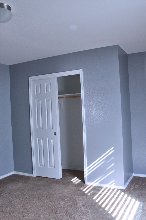 unfurnished bedroom with a closet and dark carpet