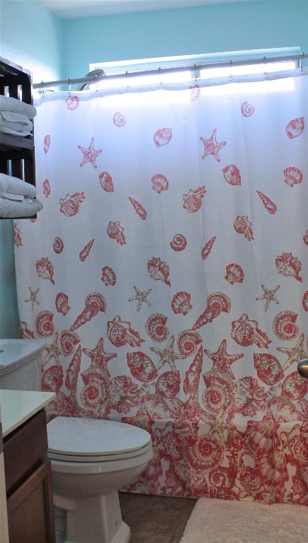 bathroom with toilet, vanity, and tile flooring