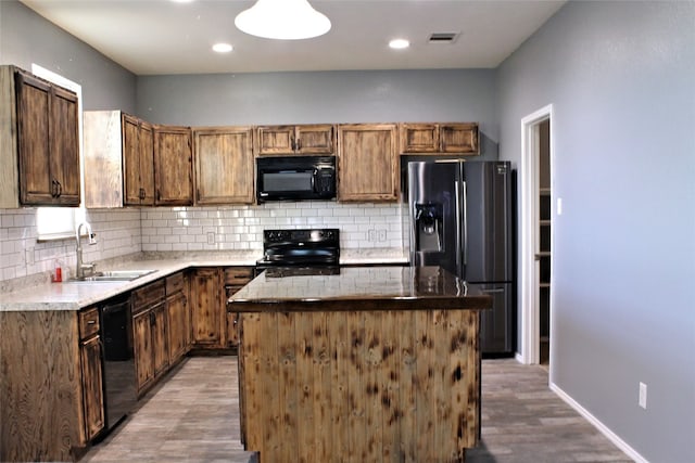 kitchen featuring a kitchen island, tasteful backsplash, light hardwood / wood-style flooring, black appliances, and sink