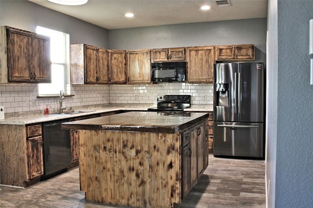 kitchen with backsplash, black appliances, wood-type flooring, sink, and a kitchen island