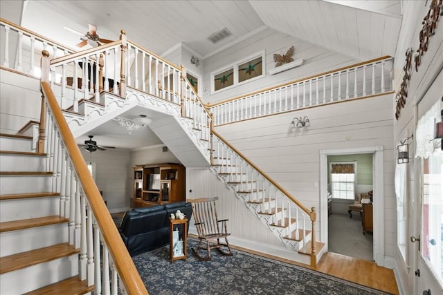 stairs featuring ceiling fan, ornamental molding, high vaulted ceiling, and hardwood / wood-style floors