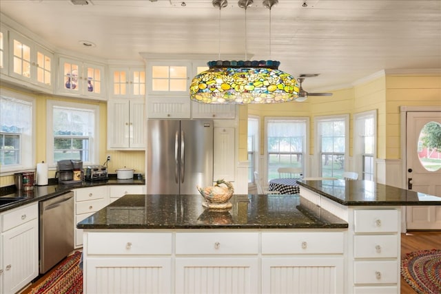 kitchen with dark stone counters, white cabinetry, hardwood / wood-style flooring, a kitchen island, and appliances with stainless steel finishes