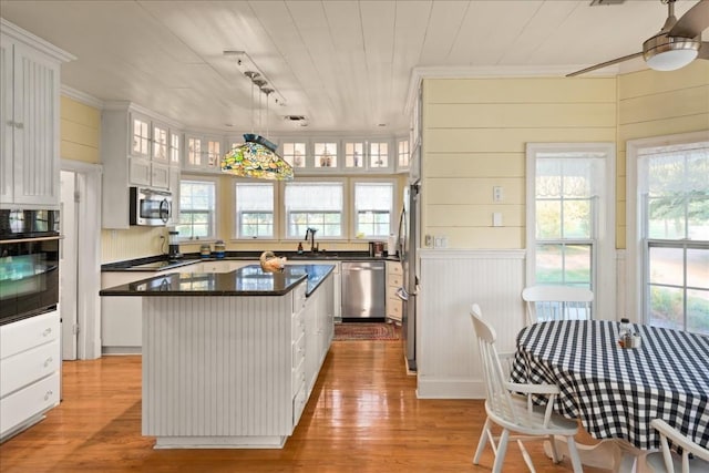 kitchen featuring pendant lighting, sink, white cabinetry, stainless steel appliances, and a kitchen island