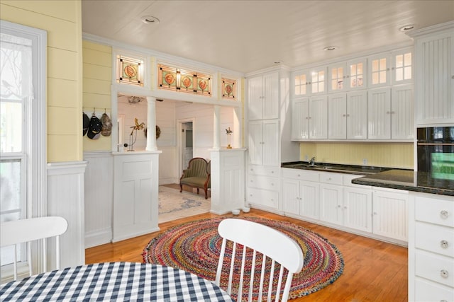 kitchen featuring oven, light hardwood / wood-style flooring, and white cabinets