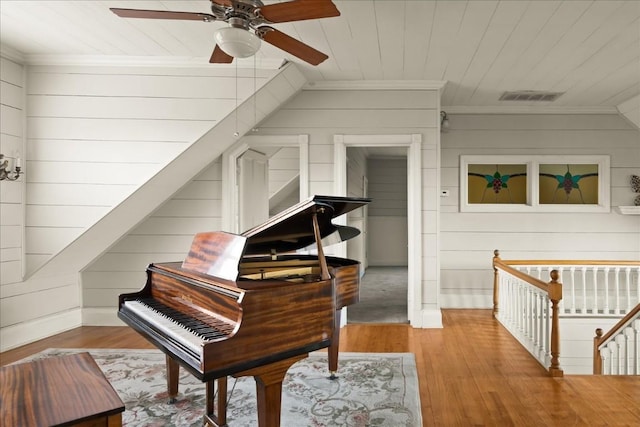 living area with crown molding, wood-type flooring, wooden ceiling, and wood walls