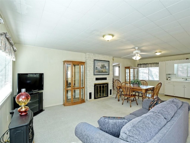 carpeted living room featuring ceiling fan, a fireplace, and sink