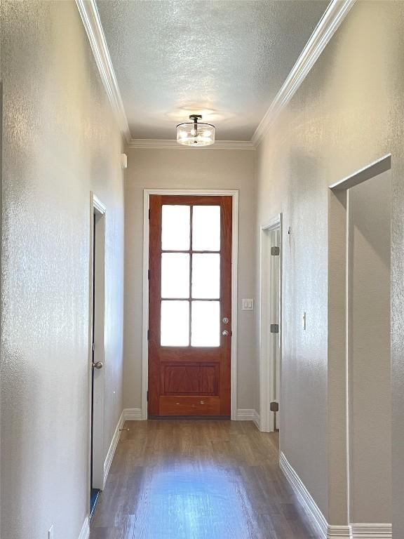 doorway featuring hardwood / wood-style flooring, ornamental molding, and a textured ceiling