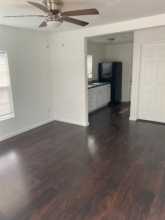 unfurnished living room featuring dark hardwood / wood-style flooring, ceiling fan, and sink