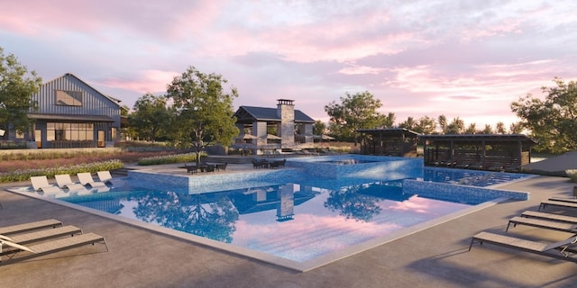 pool at dusk with a patio area and a hot tub