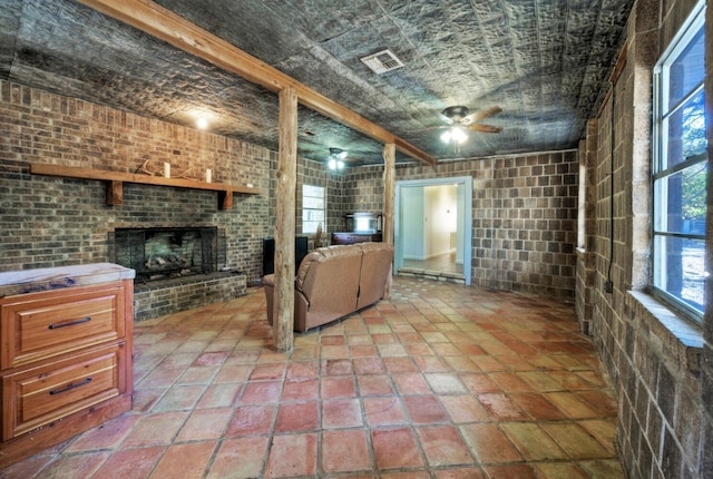 basement featuring brick wall, ceiling fan, light tile flooring, and a brick fireplace