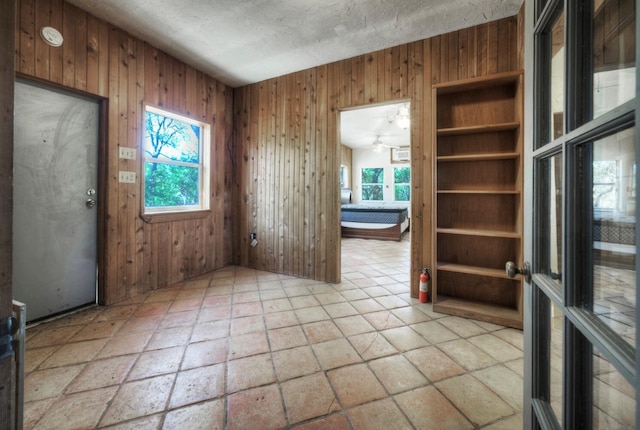 1332 Fm 969, Bastrop, TX 78602 - empty room featuring wooden walls, healthy amount of natural light, and a textured ceiling