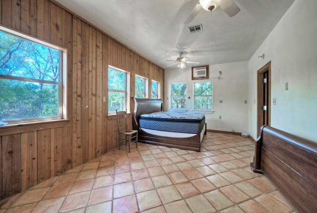 interior space featuring light tile flooring, wood walls, ceiling fan, and multiple windows