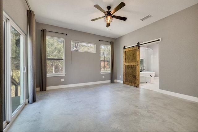 spare room with a barn door and ceiling fan