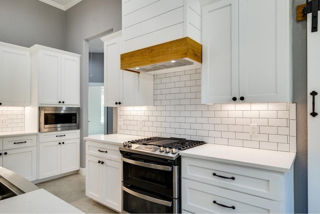 kitchen with white cabinets, premium range hood, tasteful backsplash, and stainless steel appliances