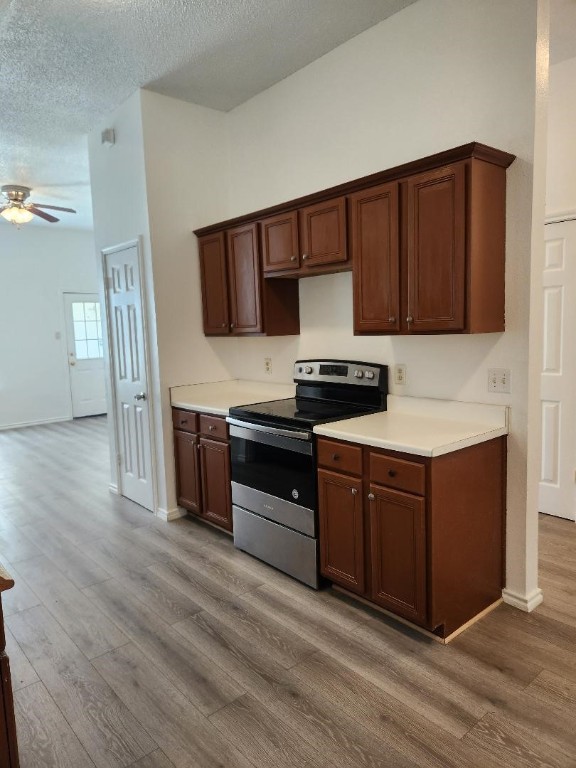 kitchen with a textured ceiling, light hardwood / wood-style flooring, electric stove, and ceiling fan