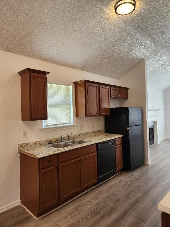 kitchen with a textured ceiling, refrigerator, dishwasher, light hardwood / wood-style floors, and sink