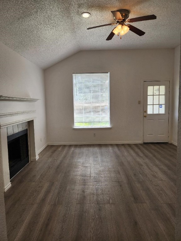 unfurnished living room featuring lofted ceiling, a textured ceiling, ceiling fan, hardwood / wood-style floors, and a tiled fireplace