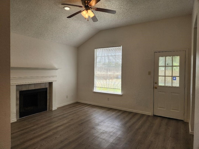 unfurnished living room featuring ceiling fan, a textured ceiling, dark hardwood / wood-style flooring, lofted ceiling, and a tiled fireplace