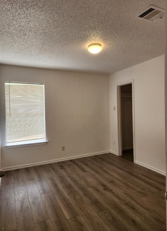 unfurnished room with a textured ceiling and wood-type flooring