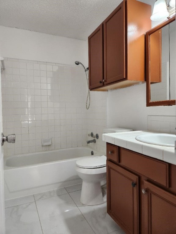 full bathroom with tiled shower / bath, a textured ceiling, toilet, tile patterned floors, and vanity