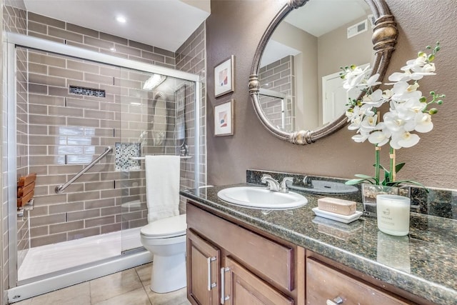 bathroom featuring toilet, vanity, tile patterned flooring, and a shower with shower door