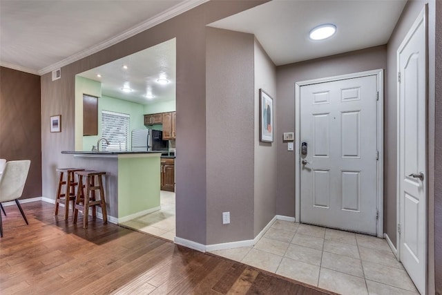 entrance foyer with crown molding, light hardwood / wood-style floors, and sink