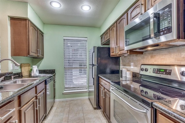 kitchen with decorative backsplash, light tile patterned flooring, sink, stainless steel appliances, and a textured ceiling