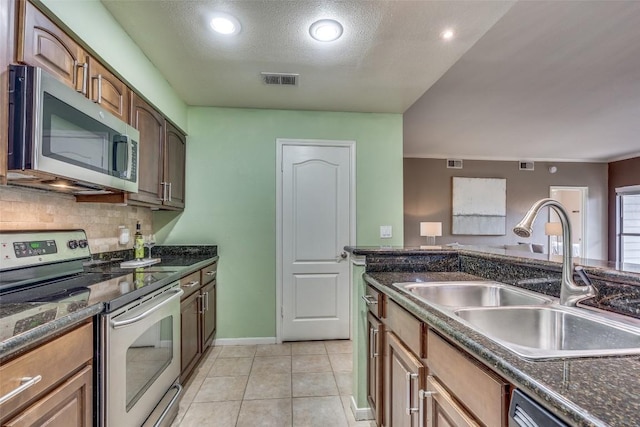 kitchen featuring a textured ceiling, appliances with stainless steel finishes, tasteful backsplash, sink, and light tile patterned floors