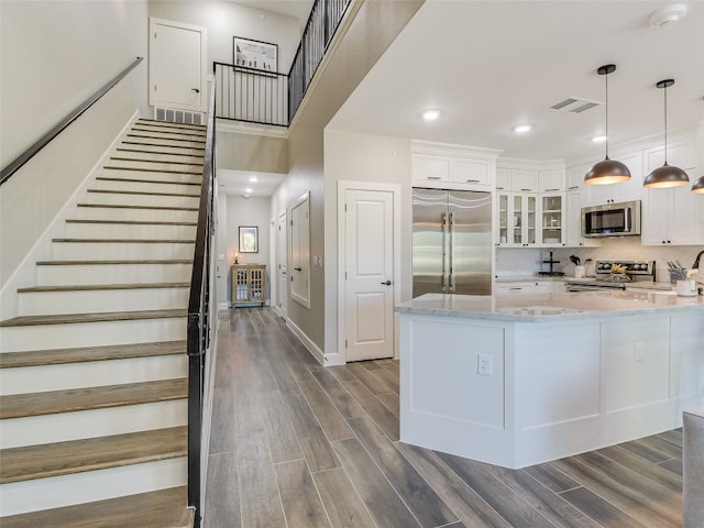 kitchen featuring light stone counters, decorative light fixtures, dark wood-type flooring, white cabinetry, and stainless steel appliances