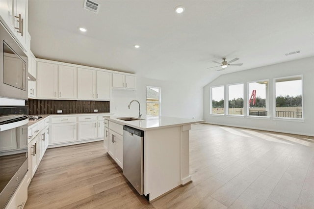 kitchen with appliances with stainless steel finishes, ceiling fan, a kitchen island with sink, sink, and light wood-type flooring