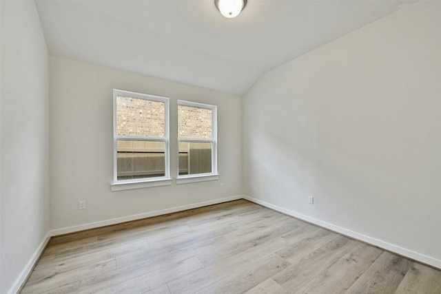 empty room with vaulted ceiling and light hardwood / wood-style flooring