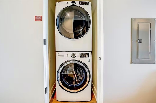 washroom with light hardwood / wood-style floors and stacked washer / drying machine