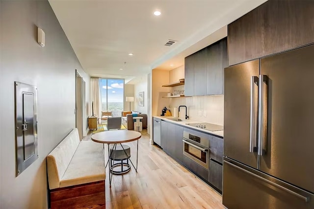 kitchen featuring backsplash, light hardwood / wood-style flooring, appliances with stainless steel finishes, and sink