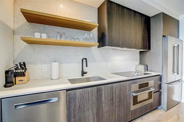 kitchen with backsplash, sink, light wood-type flooring, stainless steel appliances, and dark brown cabinetry