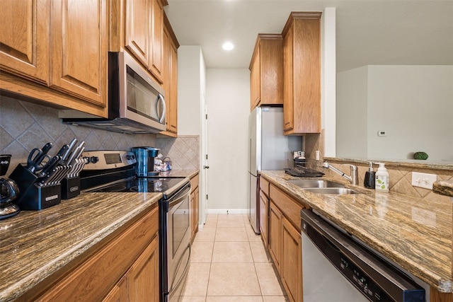 kitchen featuring light stone countertops, light tile patterned floors, appliances with stainless steel finishes, sink, and decorative backsplash