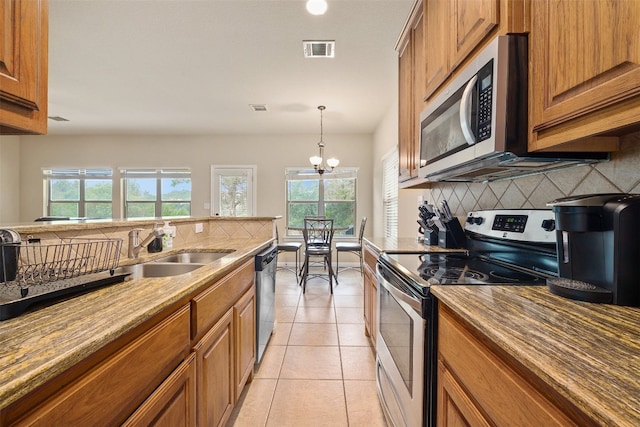 kitchen with plenty of natural light, a chandelier, decorative light fixtures, and stainless steel appliances