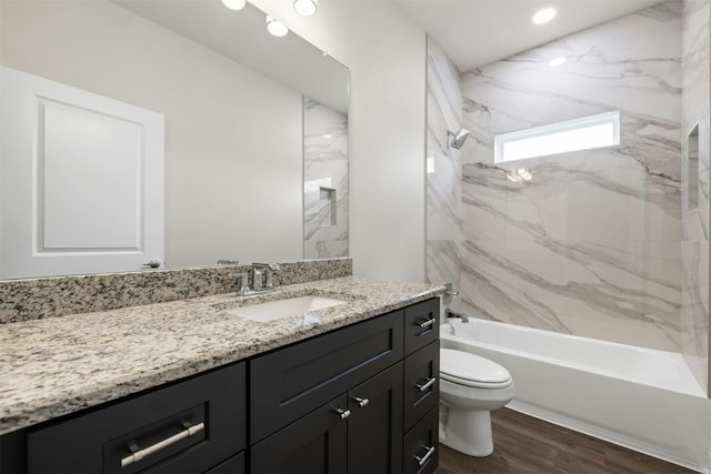 full bathroom featuring toilet, hardwood / wood-style floors, tiled shower / bath combo, and vanity