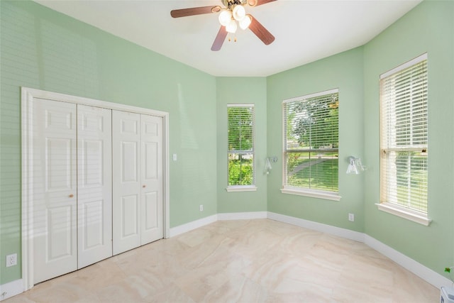 unfurnished bedroom featuring ceiling fan, a closet, and multiple windows