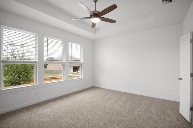 carpeted empty room with a tray ceiling and ceiling fan