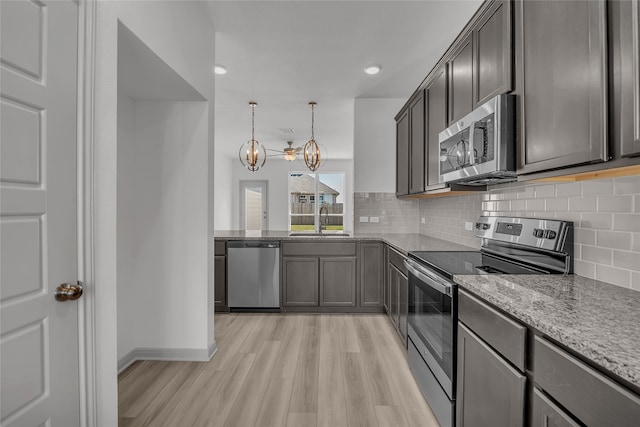 kitchen featuring appliances with stainless steel finishes, sink, light hardwood / wood-style floors, pendant lighting, and a notable chandelier