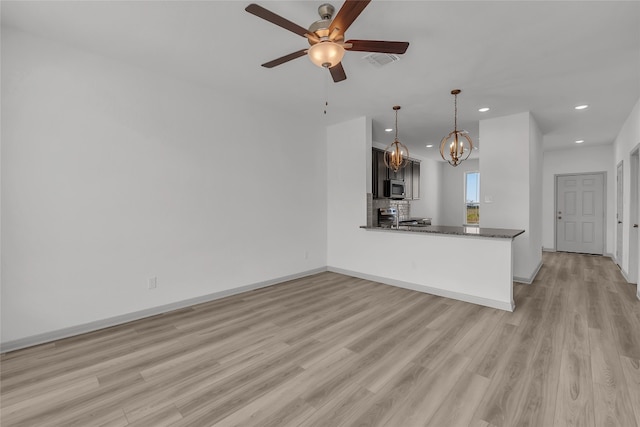 unfurnished living room featuring light hardwood / wood-style flooring and ceiling fan with notable chandelier