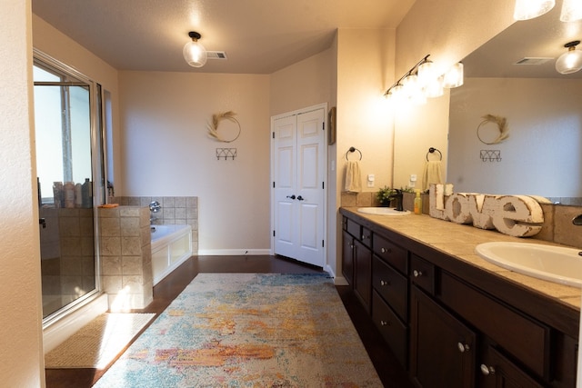 bathroom with oversized vanity, dual sinks, and shower with separate bathtub