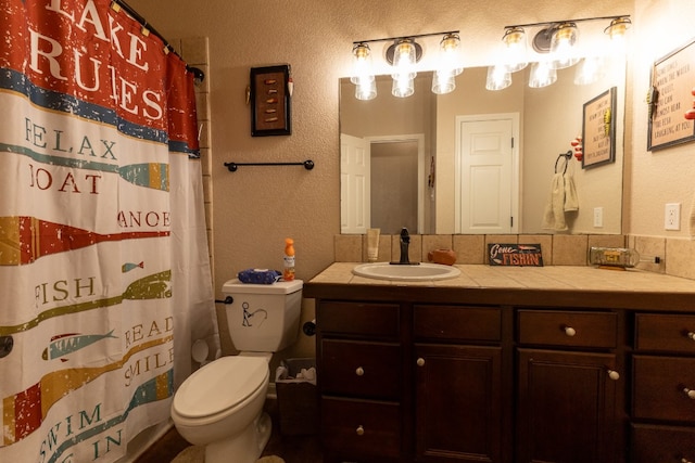 bathroom featuring backsplash, toilet, and vanity with extensive cabinet space