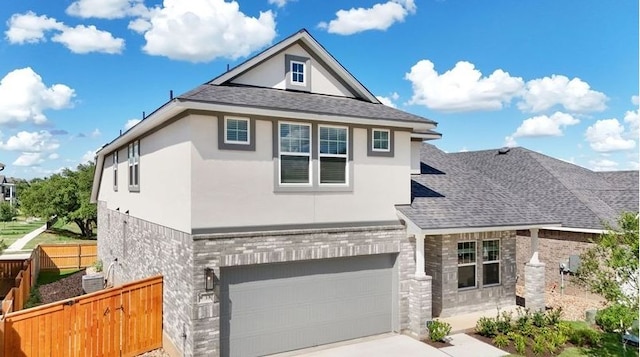 view of front facade with stone siding, stucco siding, a garage, and fence