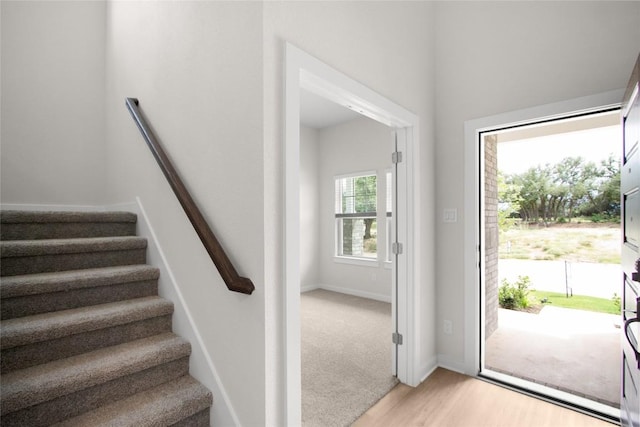 entryway with stairway, light wood-style flooring, and baseboards