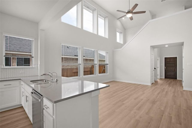 kitchen featuring a ceiling fan, a sink, white cabinetry, light wood-style floors, and dishwasher