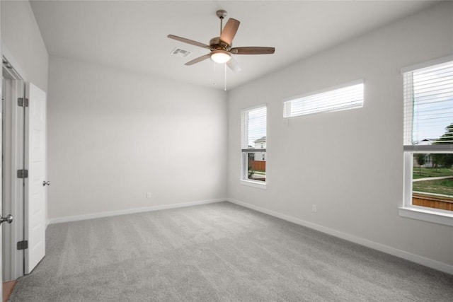 carpeted spare room with visible vents, baseboards, and a ceiling fan