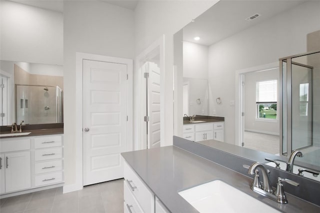 bathroom featuring tile patterned floors, two vanities, a stall shower, and a sink