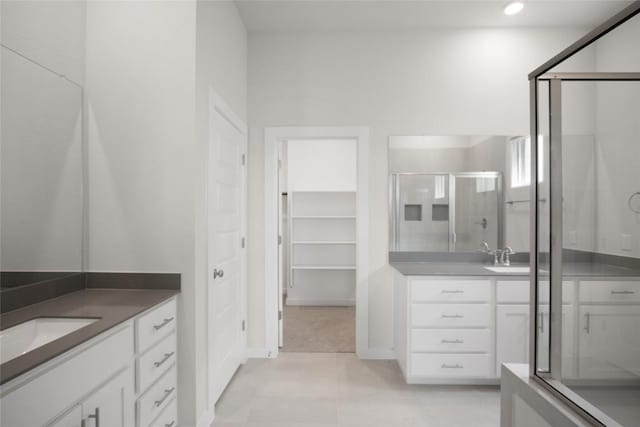 bathroom with two vanities, recessed lighting, a sink, a spacious closet, and a shower with door