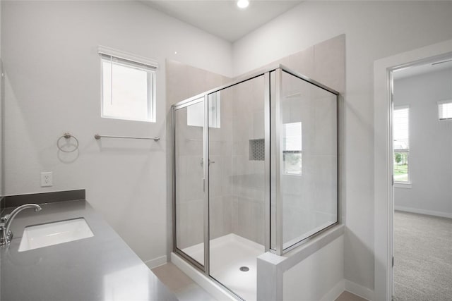 bathroom featuring a shower stall, baseboards, and a sink